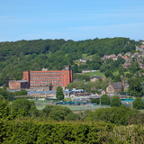 Scenic view across the Derwent valley to Belper East Mill, a large brick-built building dating to 1912, with Belper Football Club in front.