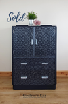 Blue tallboy cupboard, drawers below, with blue metallic stenciling